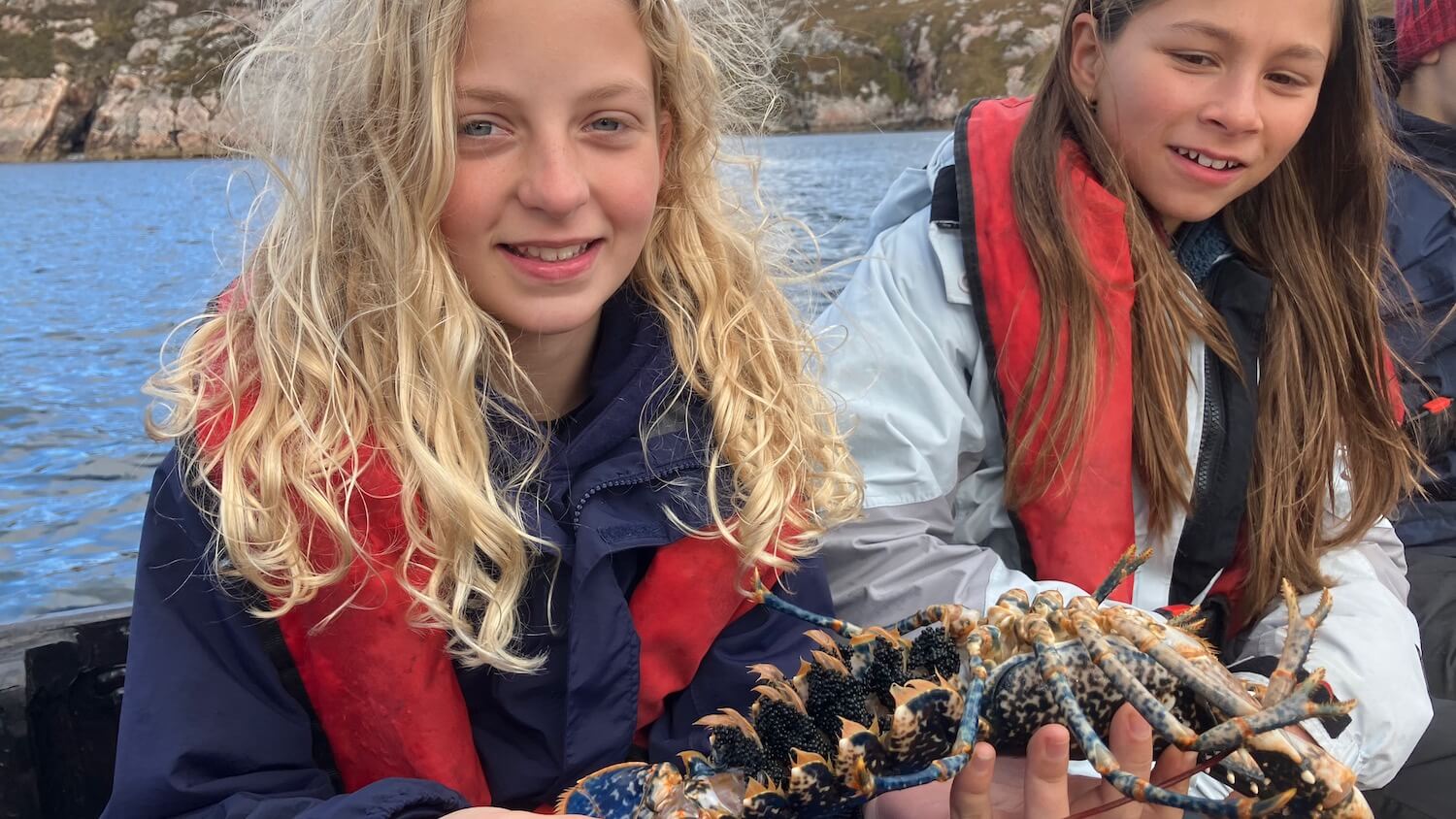 Two girls holding a lobster