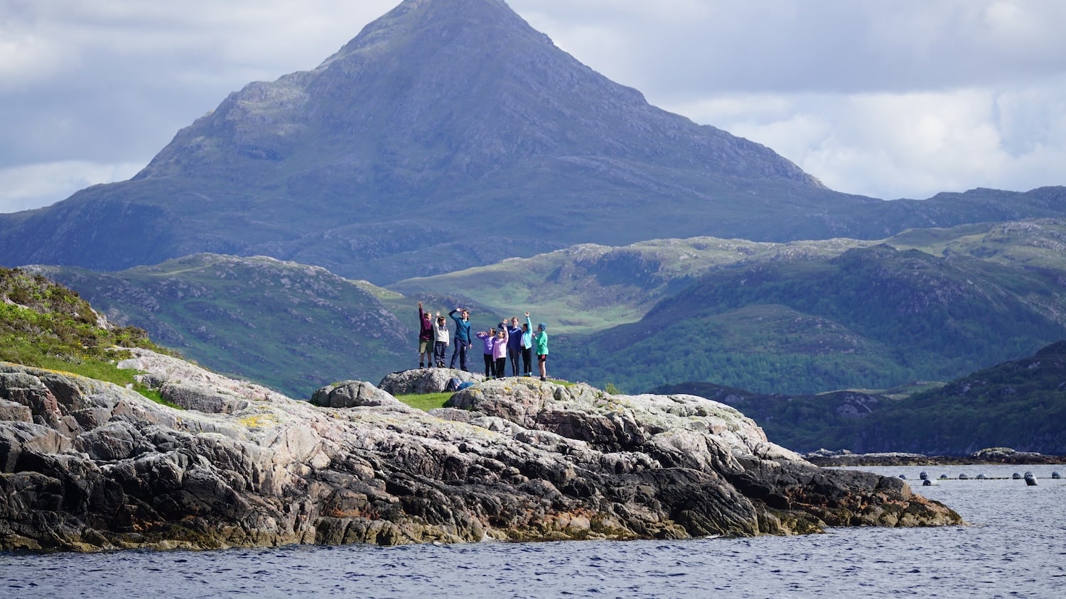 Children on a rock with mountains behind